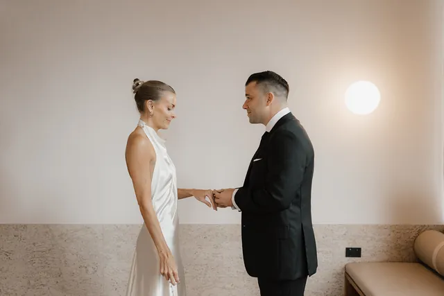 Clare and Matt holding hands and facing each other during their indoor ceremony.